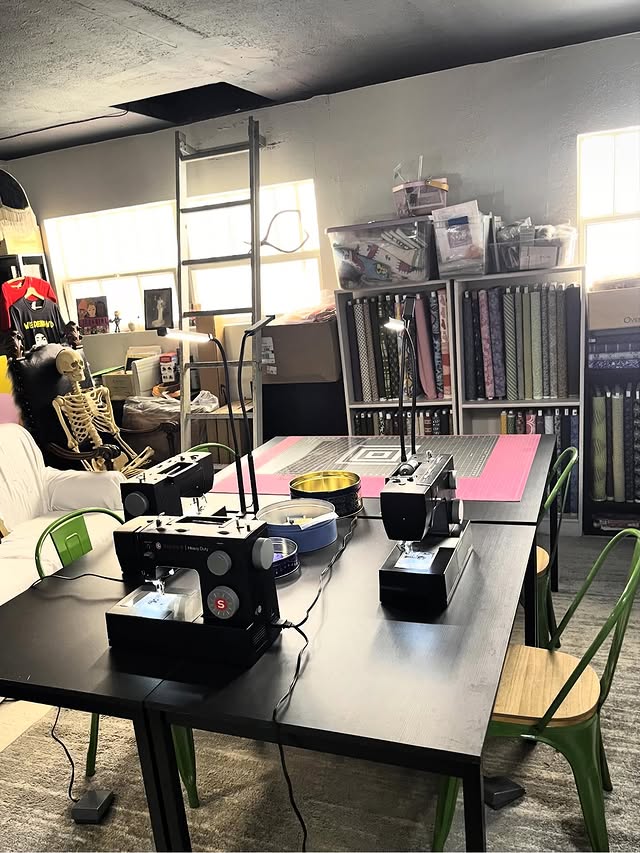 Blue Tin Fabrics workspace with a large table with sewing machines and bolt of fabric behind the table